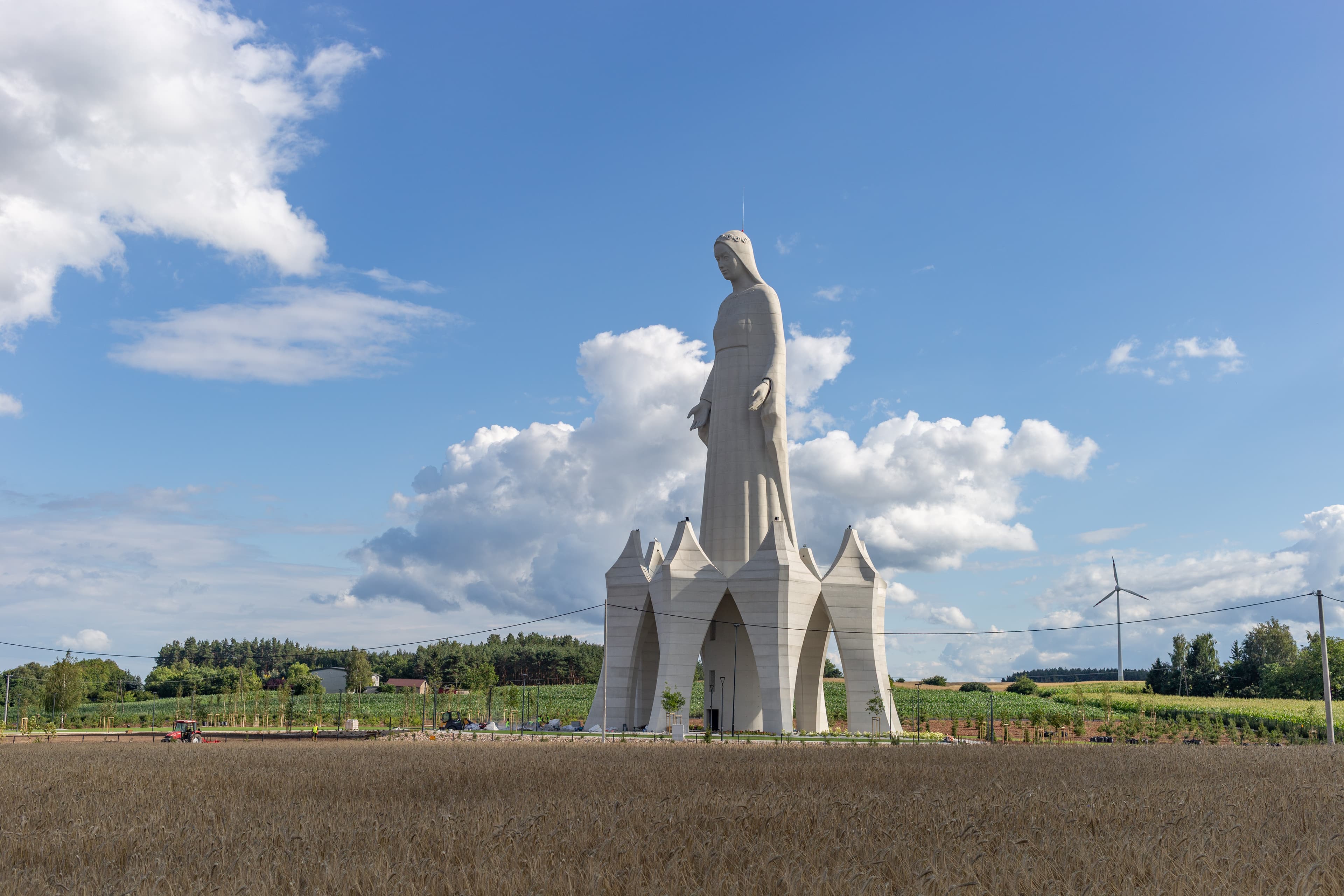 O statuie monumentală a Fecioarei Maria, amplasată într-o zonă rurală, deasupra unei construcții cu arcade. (Foto: Pko / BY-SA 4.0, Openverse)
