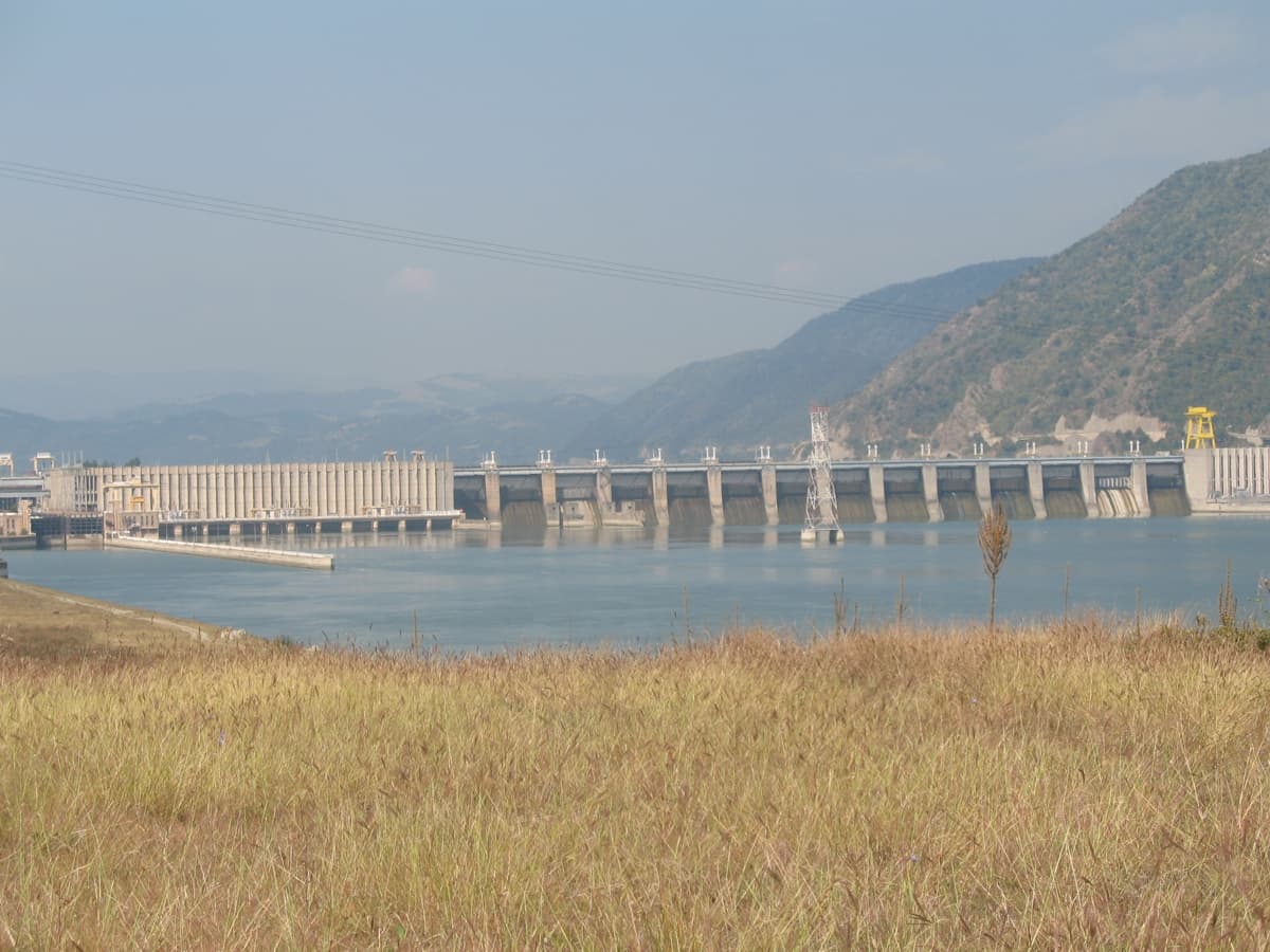 O hidrocentrală și barajul acesteia, fotografiate de pe malul unui lac de acumulare, într-o zonă montană. (Foto: CrniBombarder!!! / Public domain, Wikimedia Commons)