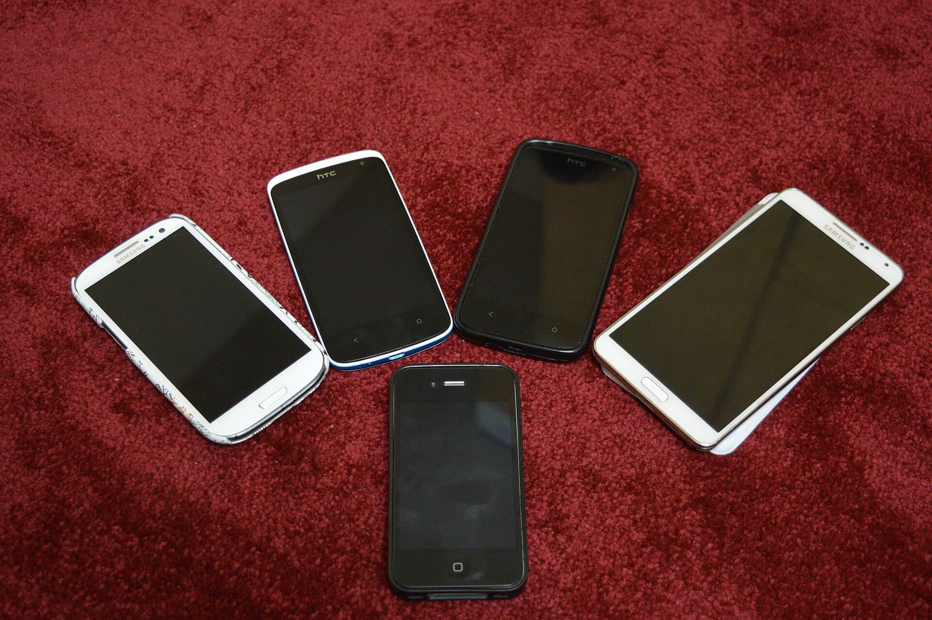 Mai multe telefoane mobile și o tabletă așezate pe un covor. (Foto de arhivă: Kskhh / CC BY-SA 4.0, Wikimedia Commons)