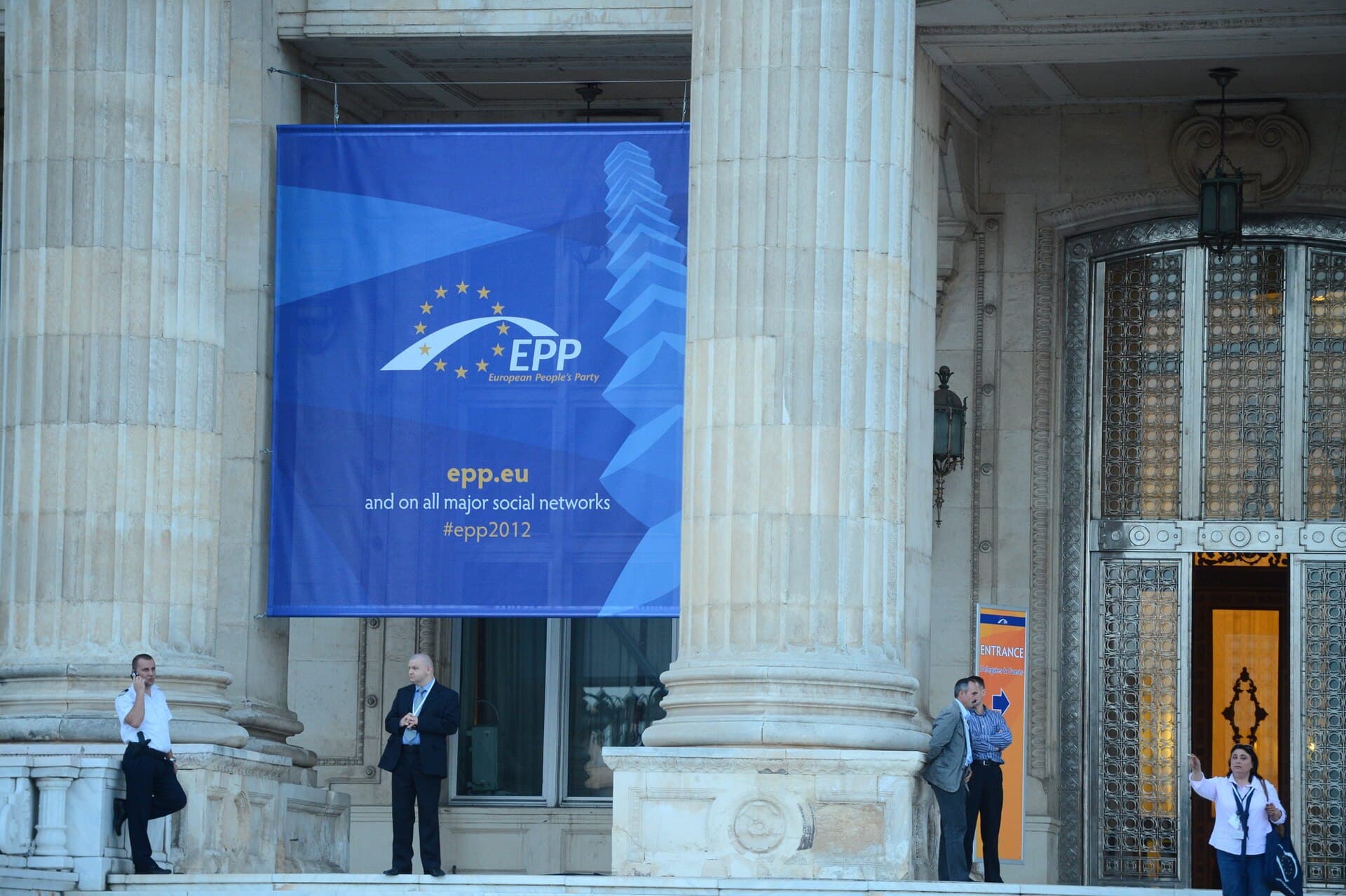 Se vede exteriorul unei clădiri oficiale cu coloane și intrare monumentală, cu un banner al Partidului Popular European (EPP) afișat pe fațadă. (Foto: European People's Party / CC BY 2.0, Wikimedia Commons)