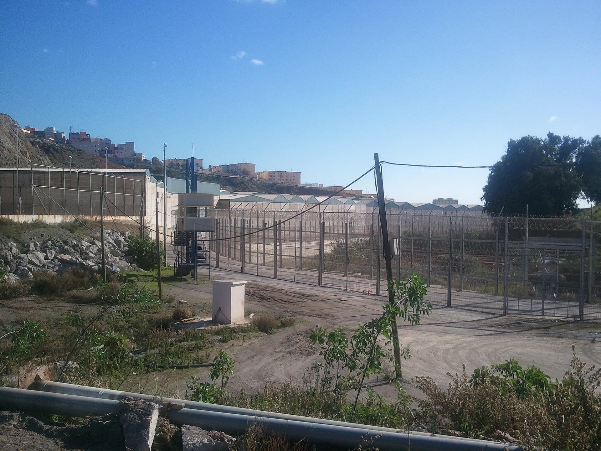 Se vede o zonă împrejmuită, cu garduri și clădiri în fundal, într-un peisaj urban de coastă, posibil în Ceuta. (Foto: Xemenendura / CC BY-SA 3.0, Wikimedia Commons)