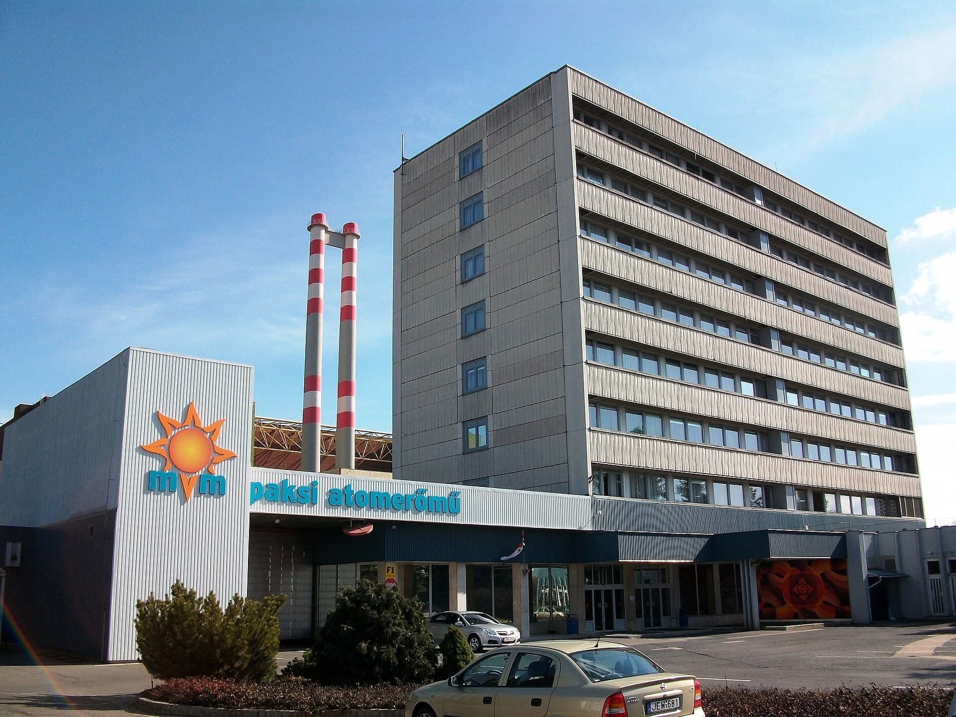 Clădirea și instalațiile exterioare ale centralei nucleare Paks, inclusiv coșurile cu dungi roșii și albe și sigla centralei. (Foto: Barna Rovács (Rovibroni) / CC BY-SA 4.0, Wikimedia Commons)