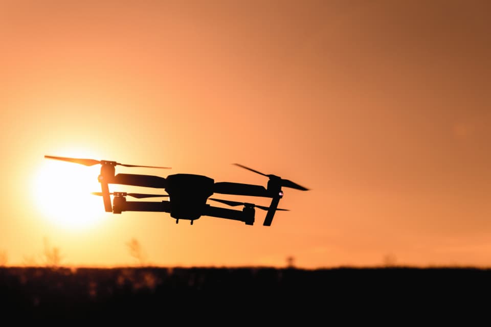 O dronă fotografiată în siluetă, în zbor, pe fundalul unui apus. (Foto ilustrativă: JESHOOTS.com / CC0 1.0, Openverse)