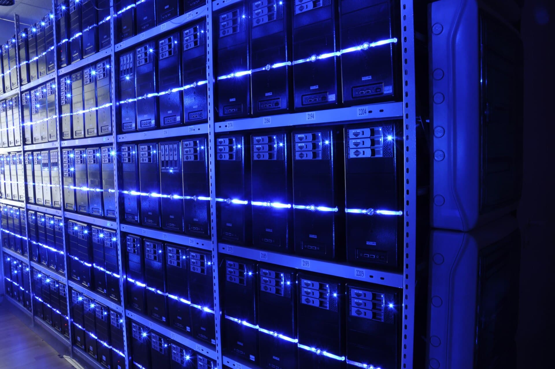 Un șir de servere și echipamente informatice într-un centru de date, iluminat cu albastru. (Foto de arhivă: BalticServers.com / CC BY-SA 3.0, Wikimedia Commons)