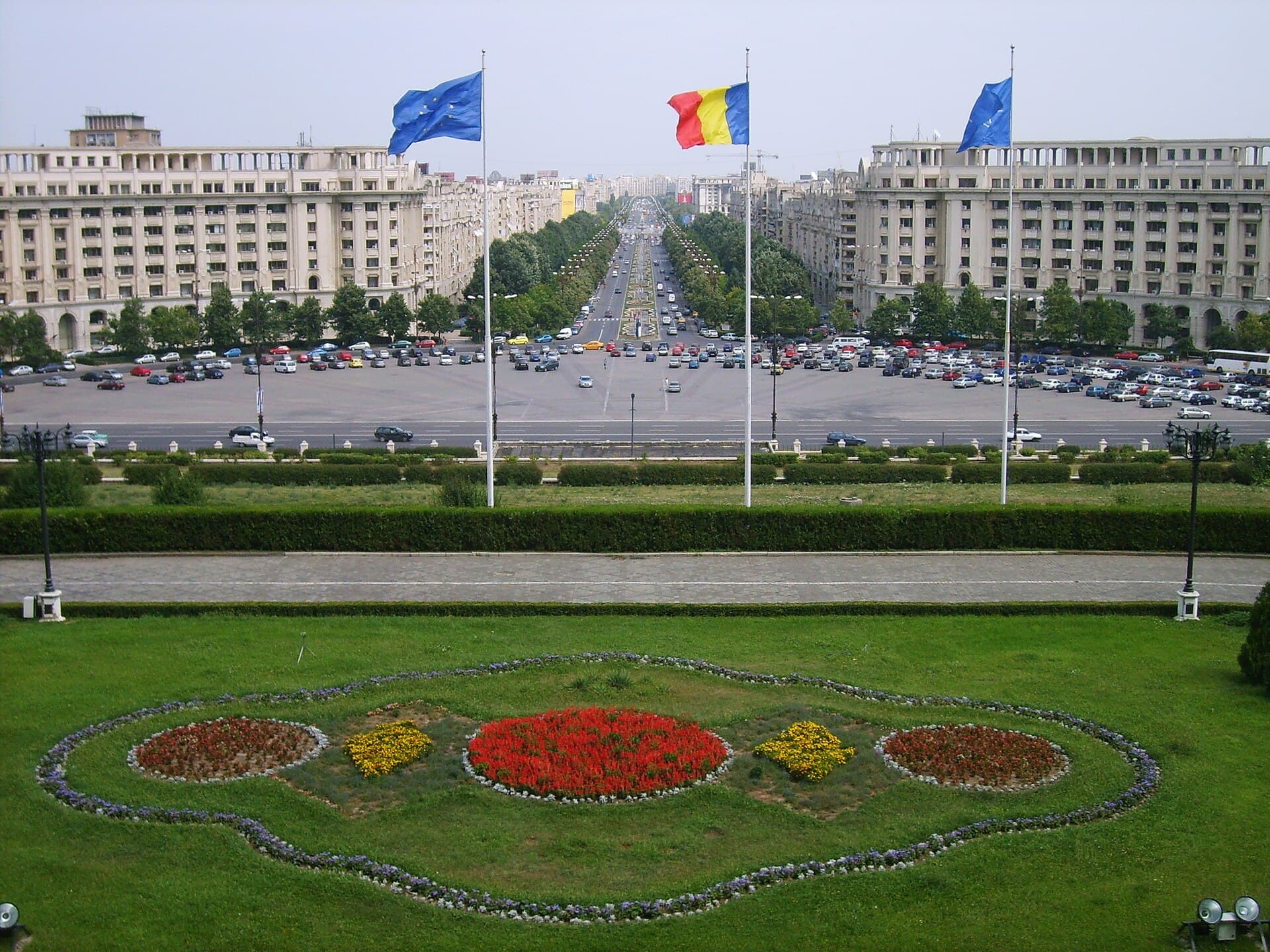 Vedere asupra unei piețe și a unor clădiri administrative din București, cu steaguri ale României și ale Uniunii Europene. (Foto: Alessio Damato / CC BY-SA 3.0, Wikimedia Commons)