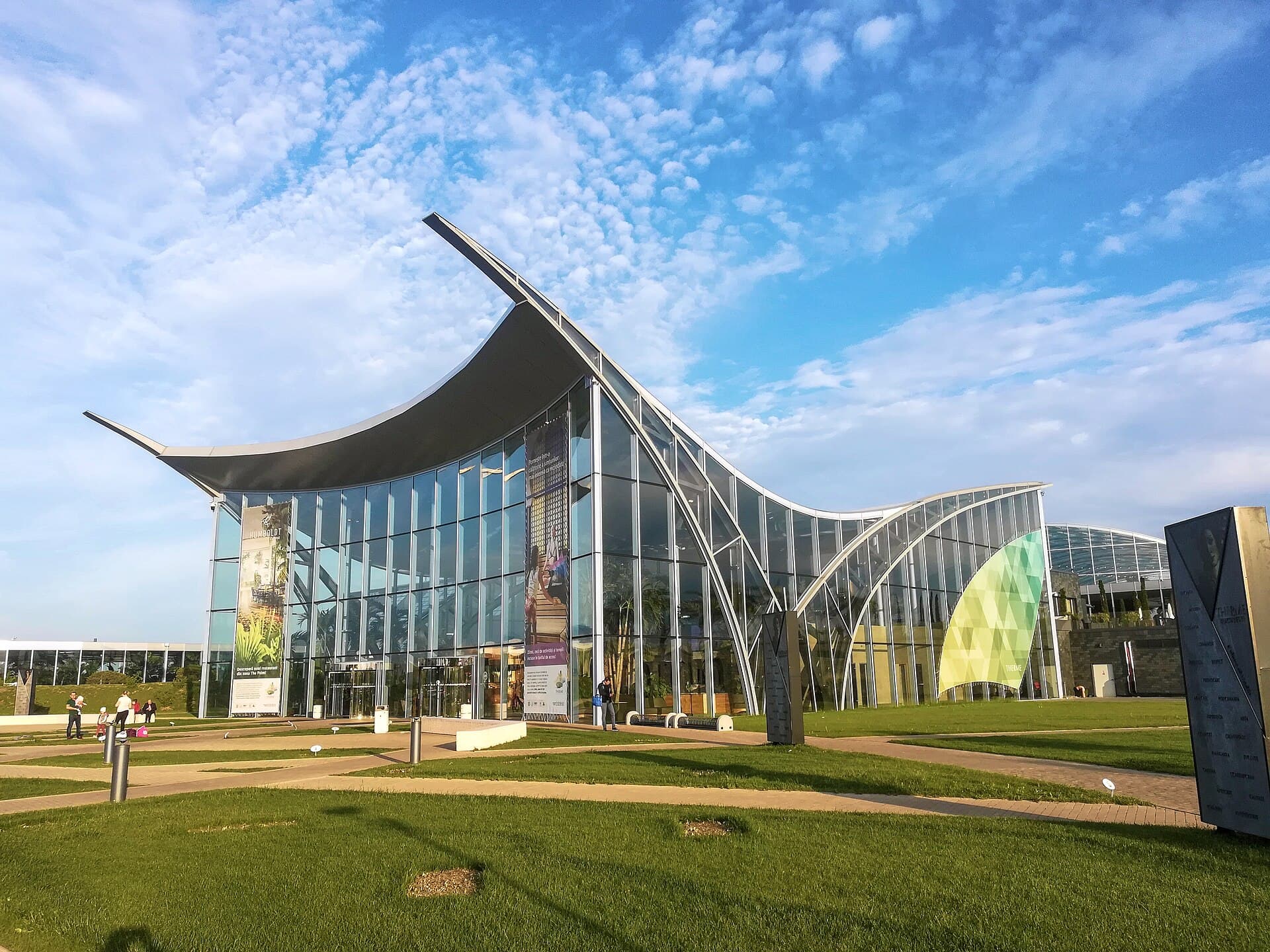 Exteriorul complexului Therme București, cu clădirea modernă și spațiul verde din față. (Foto: Daniele Napolitano / CC BY-SA 4.0, Wikimedia Commons)