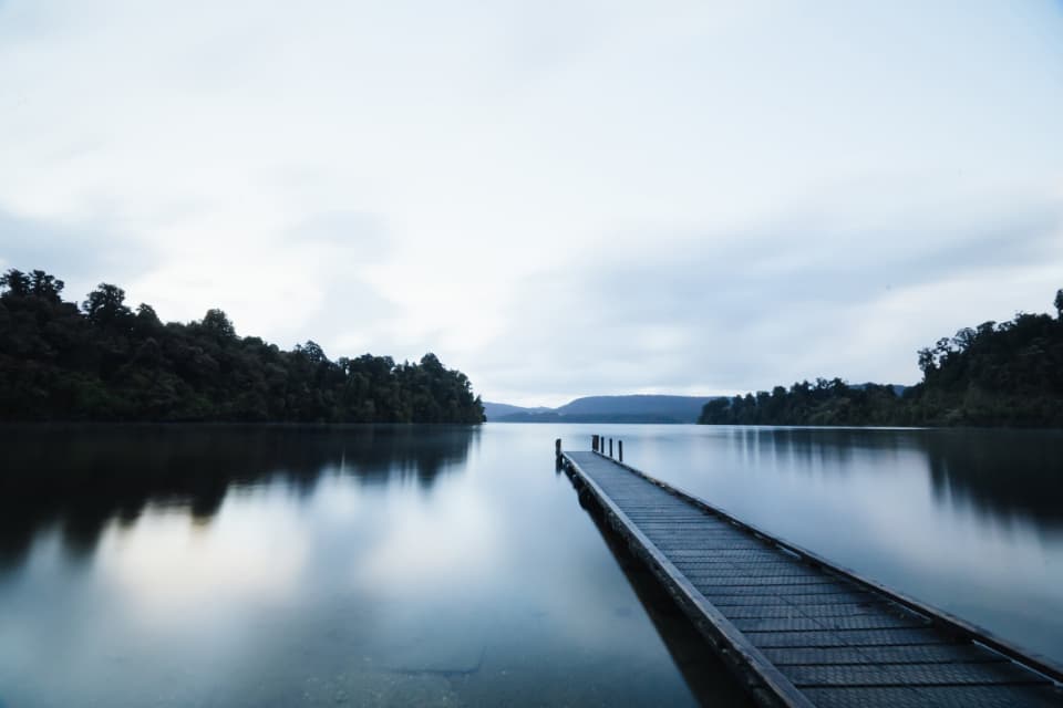 Un lac întins, cu un ponton care se prelungește în apă și maluri împădurite. (Foto ilustrativă: Burst / CC0 1.0, Openverse)