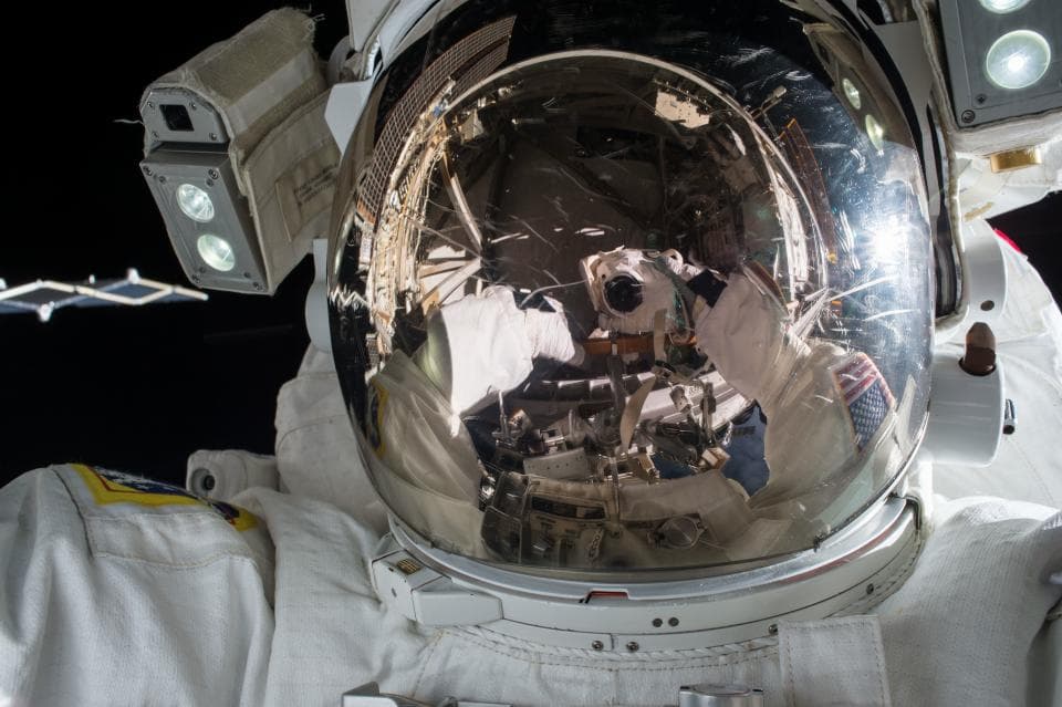 Un astronaut în costum spațial, fotografiat de aproape, cu reflexia camerei în viziera căștii. (Foto ilustrativă: NASA / CC0 1.0, Openverse)