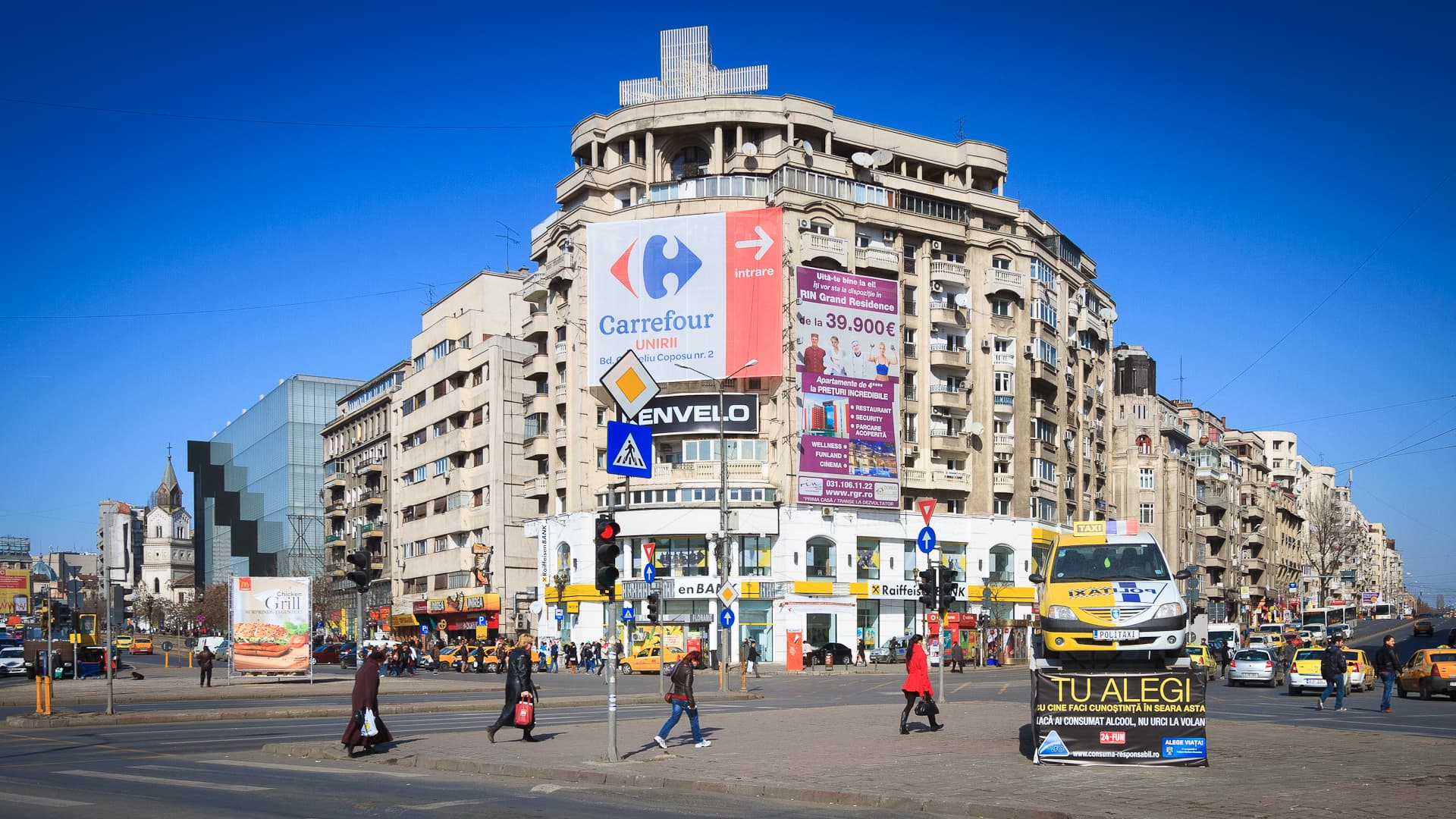 Intersecție aglomerată din Piața Unirii, cu pietoni, mașini, autobuze și clădiri comerciale. (Foto: Mihai Petre / CC BY-SA 3.0, Wikimedia Commons)