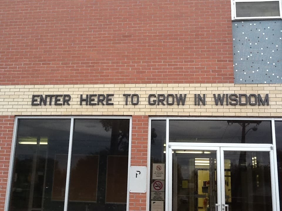 Intrarea unei școli, cu mesajul „ENTER HERE TO GROW IN WISDOM” pe fațadă. (Foto de arhivă: jdog90 / BY 2.0, Openverse)