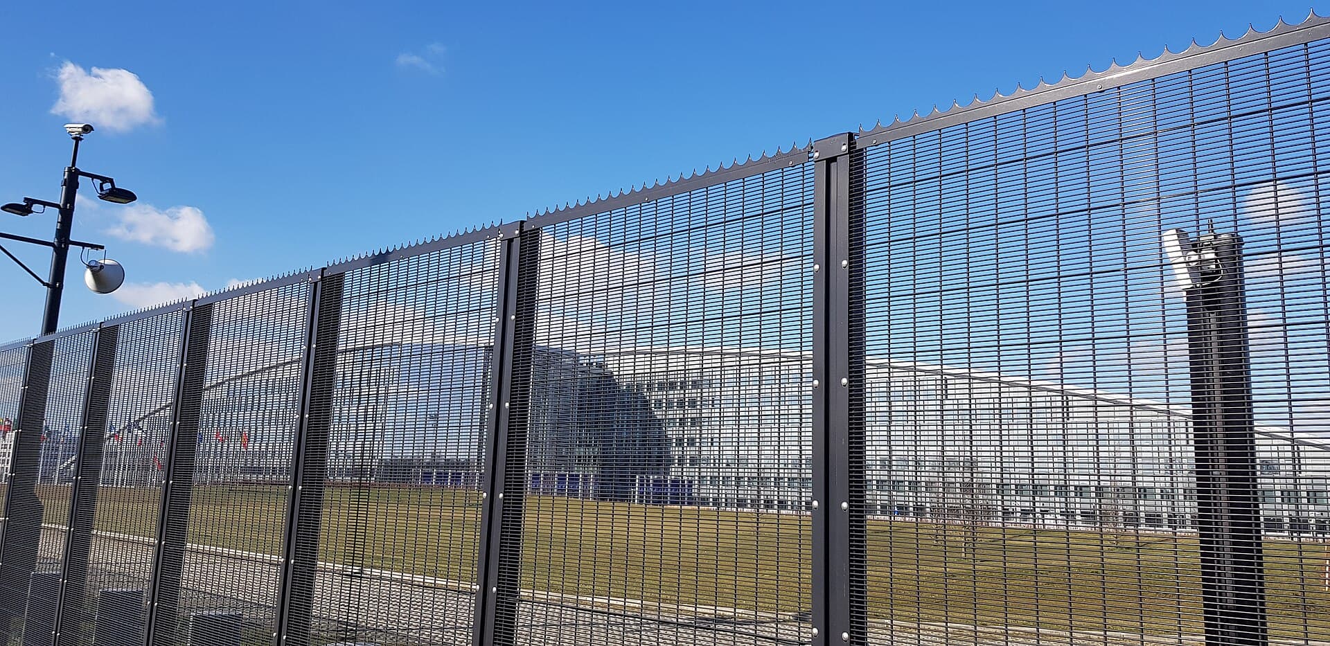 Un complex modern securizat, identificabil ca sediul NATO din Bruxelles, văzut din exterior, în spatele unui gard. (Foto: Romaine / CC0, Wikimedia Commons)