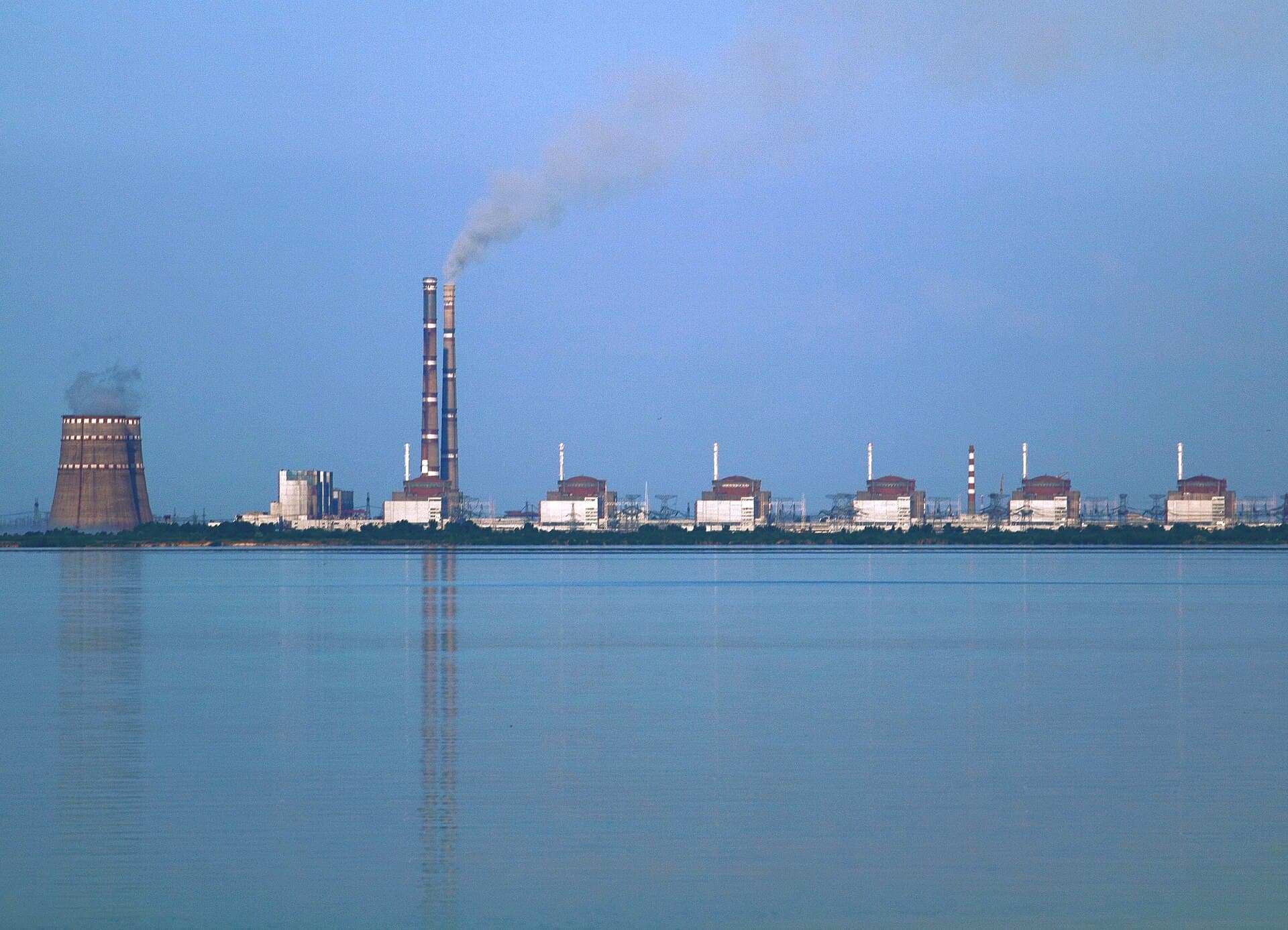 O centrală nucleară cu mai multe reactoare și un turn de răcire, văzută de peste un luciu de apă. (Foto: Ralf1969 / CC BY-SA 3.0, Wikimedia Commons)