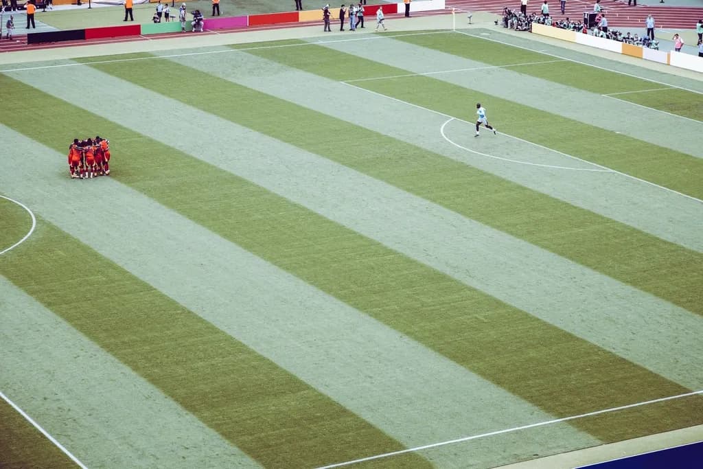 Fotografie reală de pe un teren de fotbal, cu jucători în timpul unui meci. (Foto ilustrativă: Markus Spiske / CC0 1.0, Openverse)