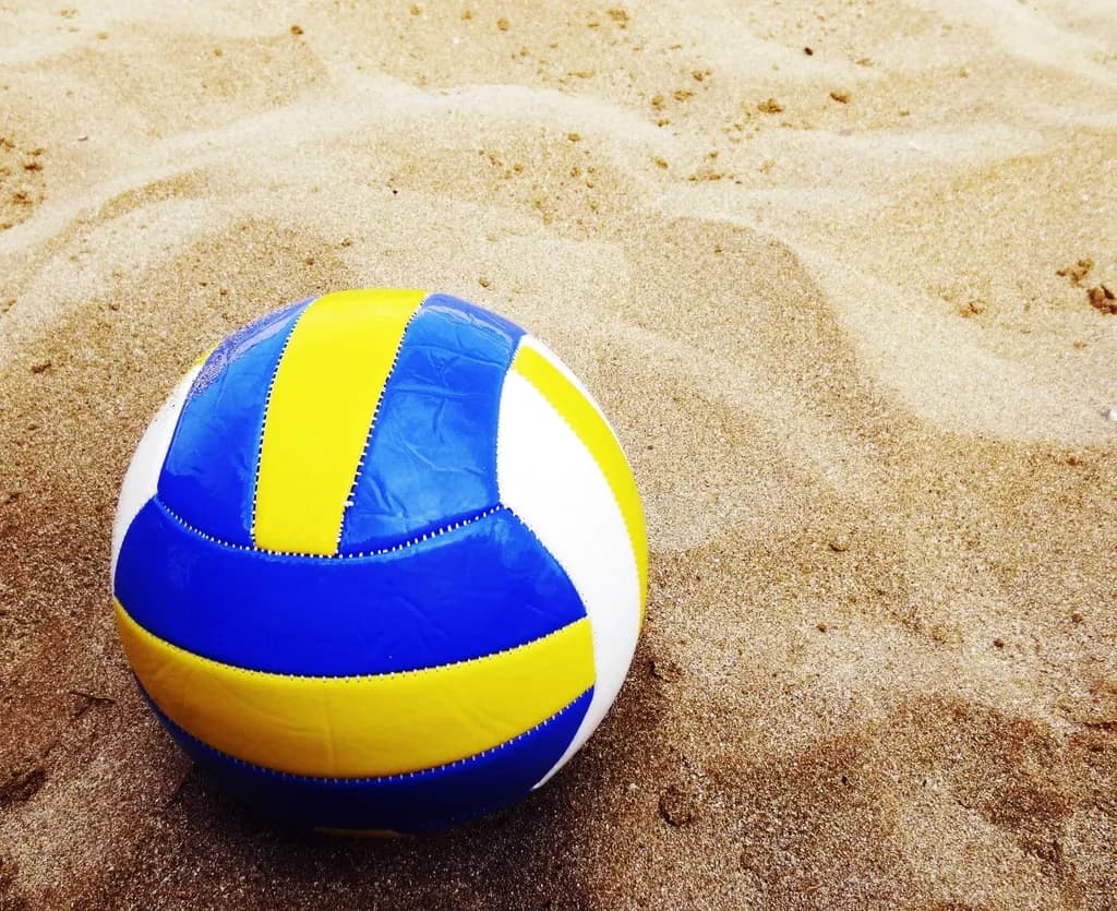 O minge de volei albastră, galbenă și albă pe nisip. (Foto ilustrativă: necunoscut / CC0 1.0, Openverse)