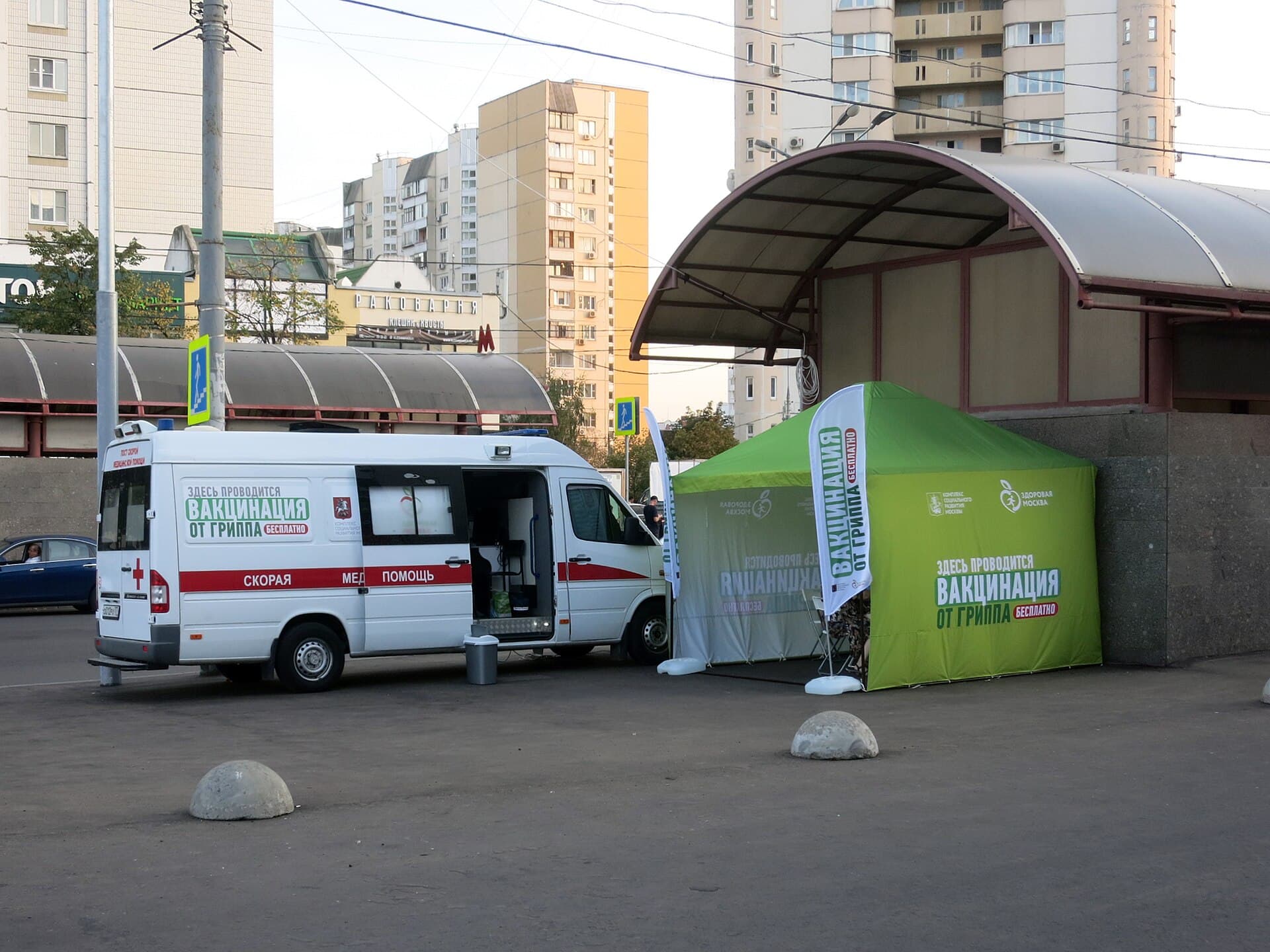 Un punct mobil de vaccinare, cu o dubă inscripționată și un cort verde de vaccinare, amplasat într-o zonă urbană. (Foto de arhivă: toiida / CC0, Wikimedia Commons)