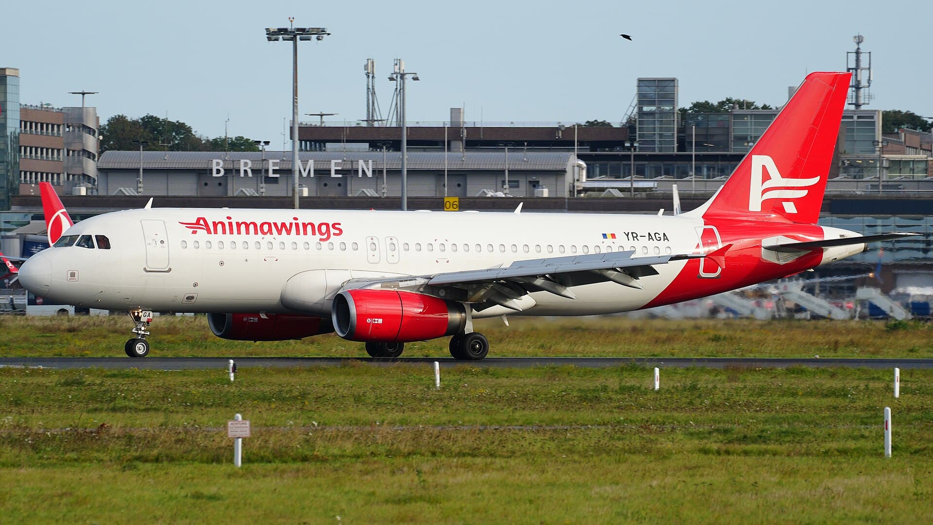 Un avion al companiei AnimaWings pe aeroport, cu clădirea terminalului în fundal. (Foto: MarcelX42 / CC BY-SA 4.0, Wikimedia Commons)